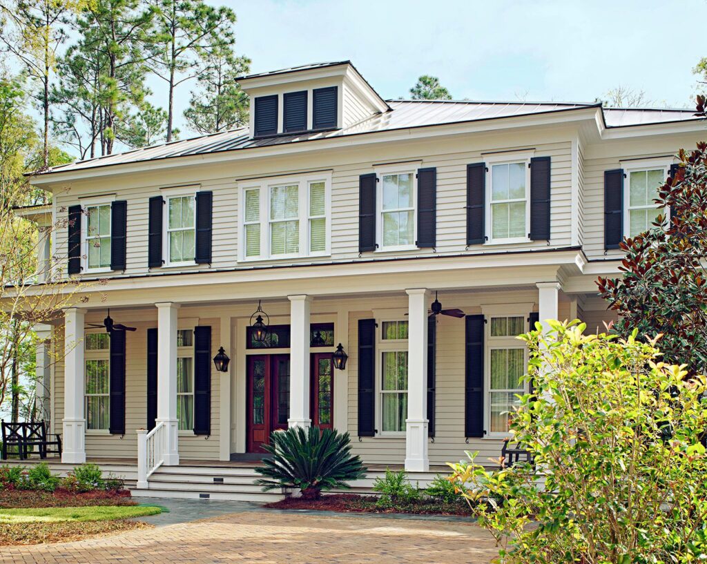 White colonial-style house with front porch columns and landscaped front yard